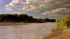 Some men are walking through a river.