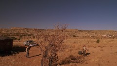 Walt rolls a barrel through the desert until he reaches a house.